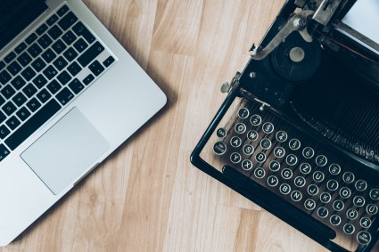 Macbook beside typewriter machine